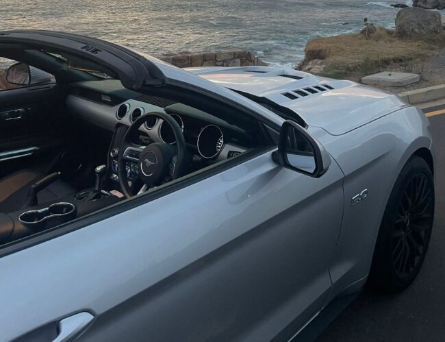 Interior view of a silver convertible sports car with a focus on the dashboard and steering wheel.